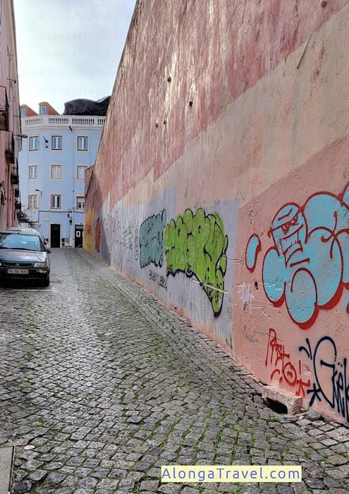 Intensely pink old wall makes very cute scene next to an old blue house in Baixa Lisbon