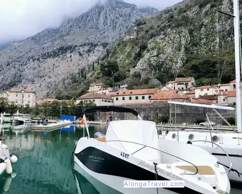 European Destinations on Alonga Travel by countries 3 A boat in a marina overlooking medieval settlement of Kotor Montenegro, under imposing mountains